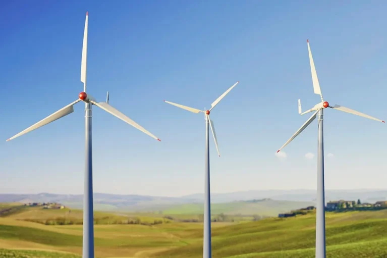 Drei Windkraftanlagen auf einem grünen Feld unter blauem Himmel